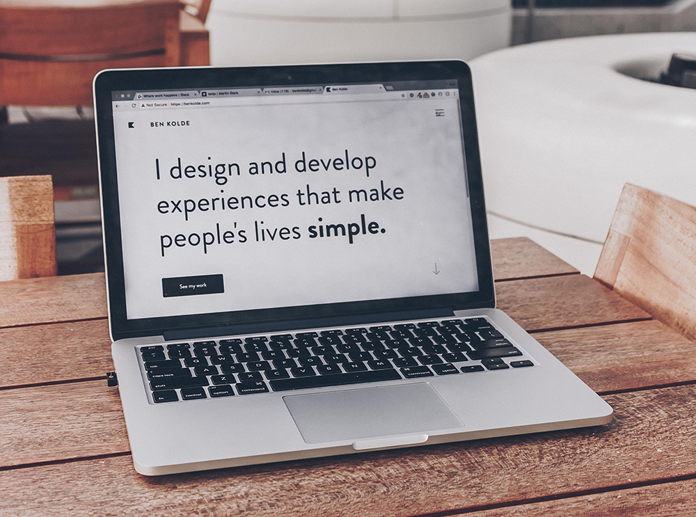 Laptop with the text 'I design and develop experiences that make people's lives simple'